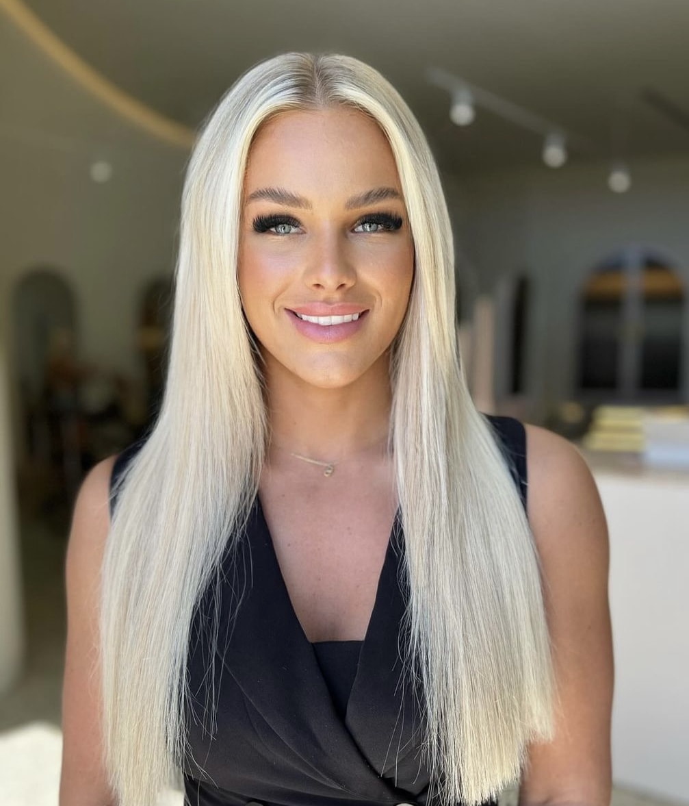 Smiling woman in a black shirt, representing the confidence and beauty achieved with Kasey Lee Blonde Specialist's hair services